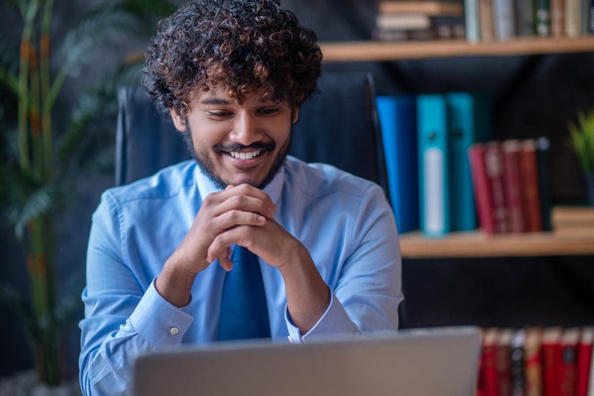 A man smiling at something on his laptop screen