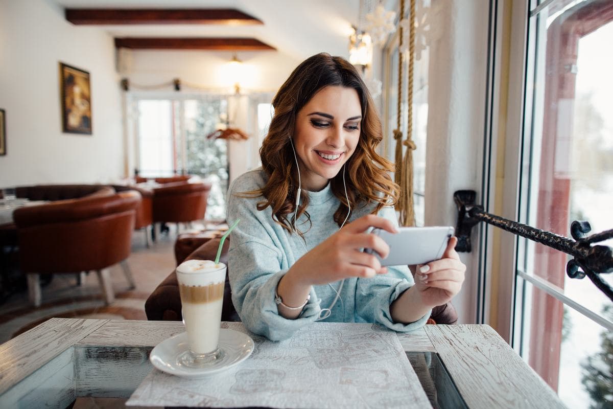 A woman at a café table recording a video on her phone